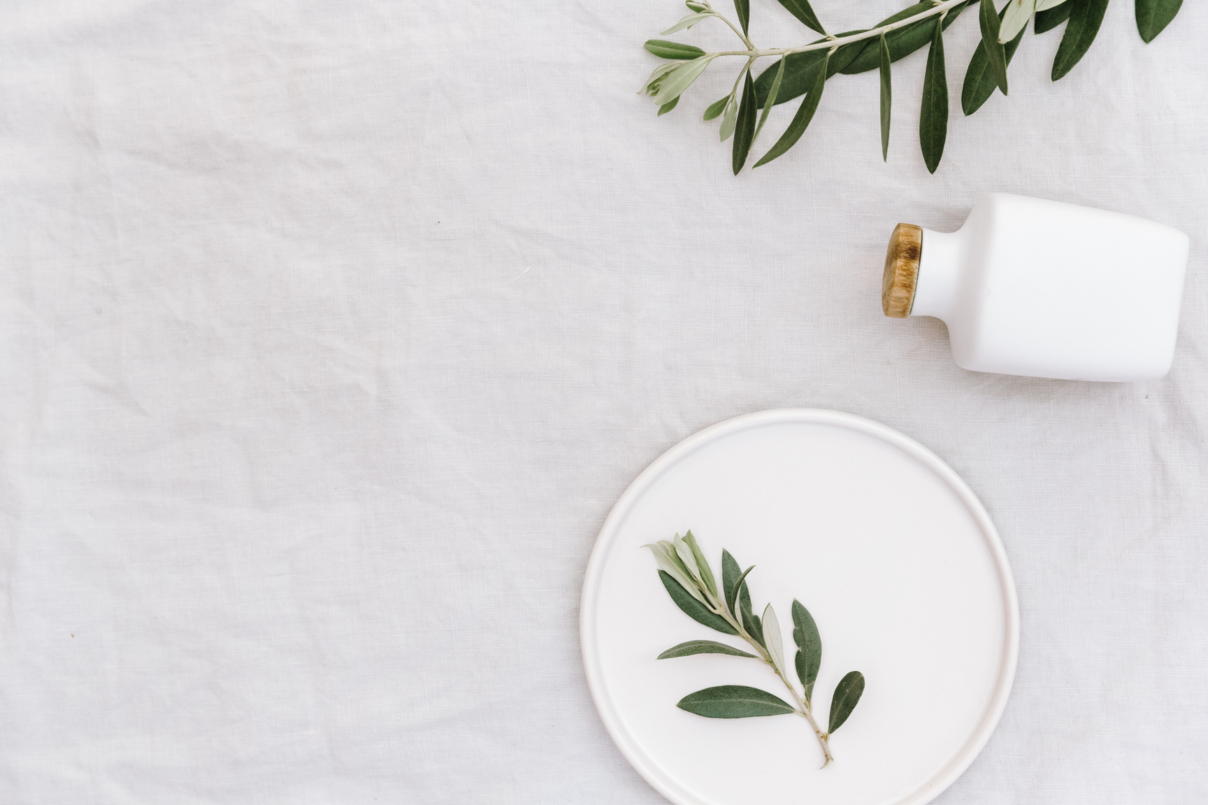 Flat lay mock up with olive branch over linen. Minimal eco concept